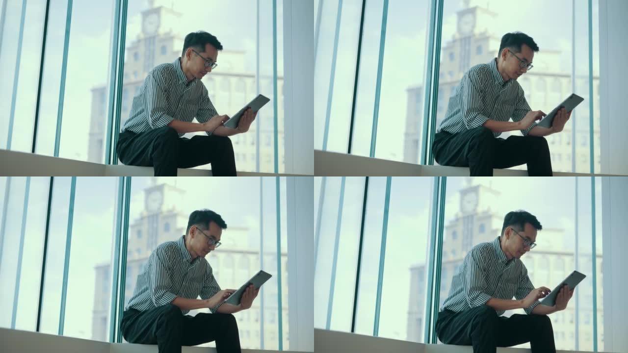 商人坐在窗户前使用数字平板电脑