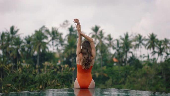 性感女人放松的游泳池穿着比基尼享受热带度假在豪华酒店度假与丛林天堂的观点4k