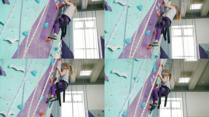 小女孩爬上人造墙在体育中心集中进行极限活动