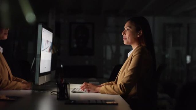 女商人晚上在电脑上工作，在公司里打字和研究技术、电脑和桌子。女性员工在黑暗的办公室、桌面和晚上在线进