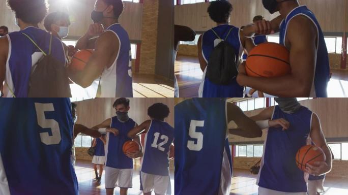 多元化的男子篮球队戴着口罩，用手肘打招呼