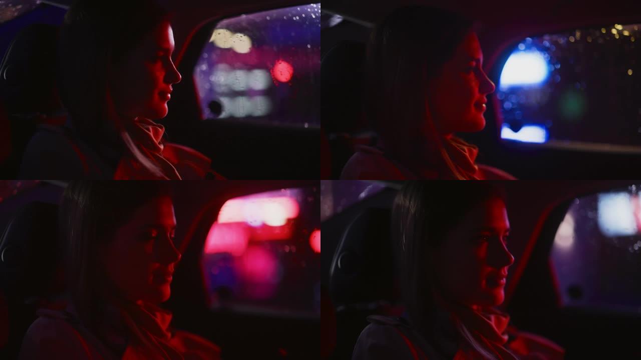 夜间在出租车后座上的女性通勤回家的特写肖像。美丽的女人乘客在城市街道上开着霓虹灯的汽车时看着窗外。电