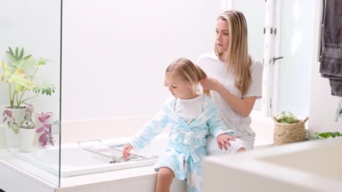 早上，母亲和女儿在浴室里用发刷在家庭中进行日常美容护理。母亲、孩子和妈妈在家里给小孩子梳头，为这一天