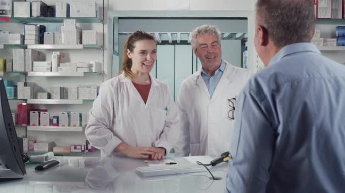 微笑的专业药剂师顾问将处方药交给药房患者的电影镜头。药店、药品、保健、药剂师、援助的概念。
