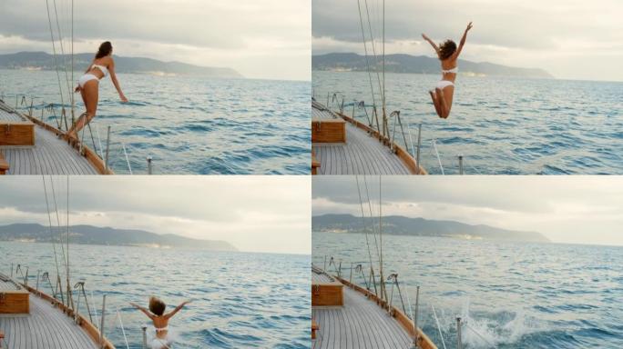 穿着白色比基尼的年轻女子兴奋地从游艇上跳入大海。在意大利航行的女人跳下游艇在海里游泳。穿着白色比基尼