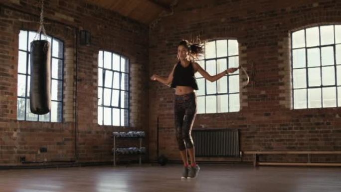 4k视频片段，一名年轻女子在健身房用跳绳锻炼