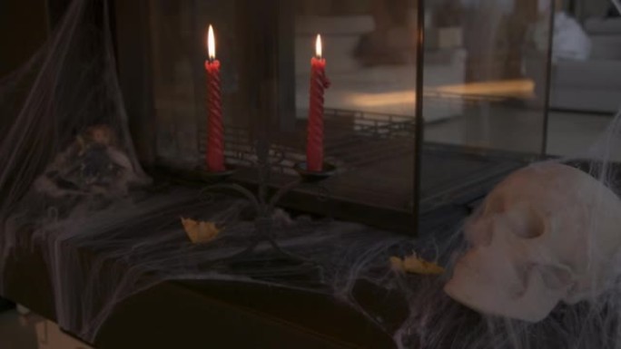 特写: 作为万圣节装饰的一部分，燃烧蜡烛和蜘蛛网覆盖的头骨