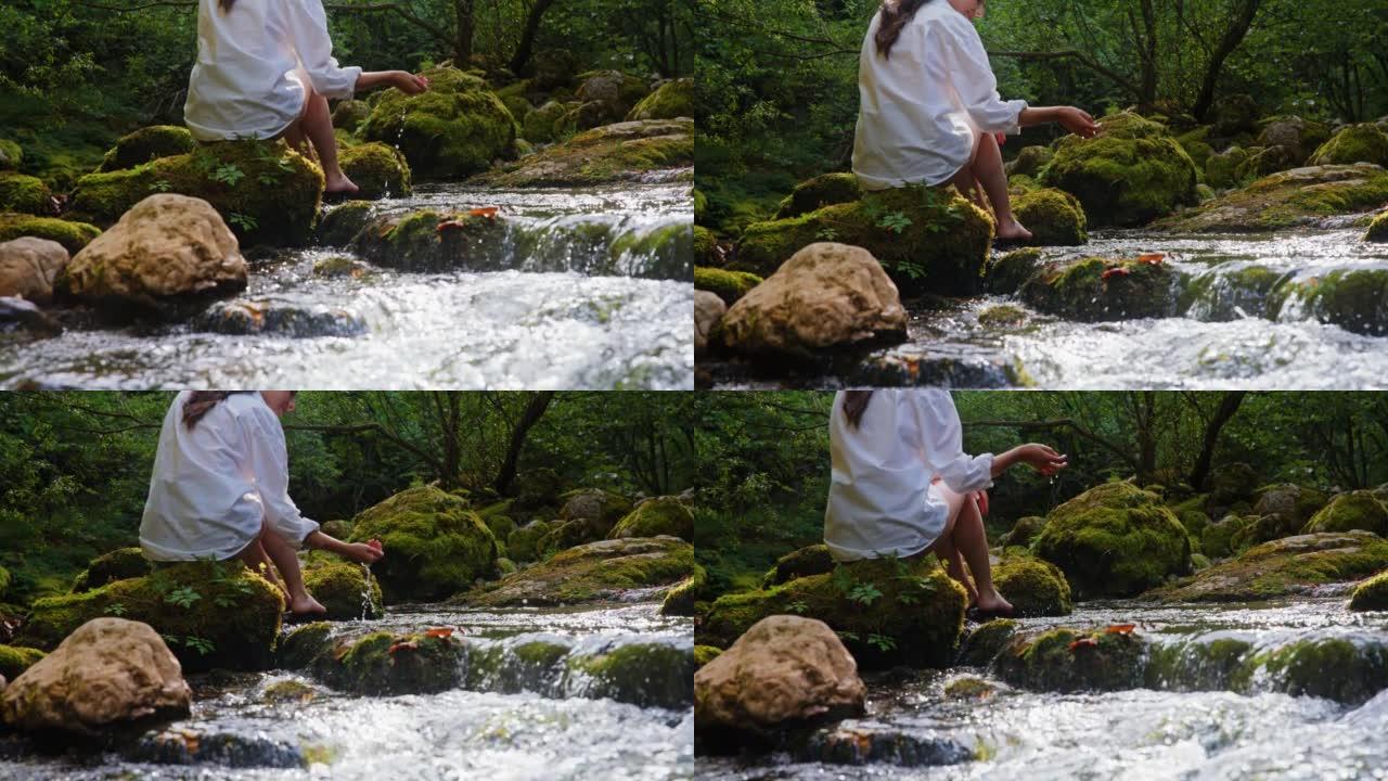 SLO MO年轻女子在森林中的溪流中放松时摸着水