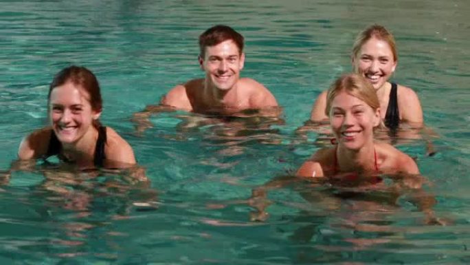 四个微笑的人在游泳池里做水上有氧运动