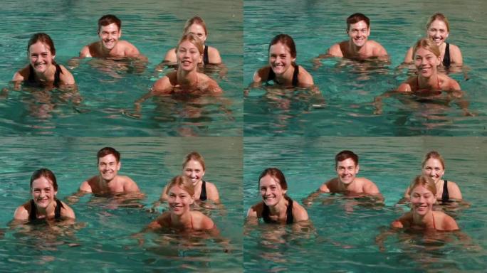 四个微笑的人在游泳池里做水上有氧运动