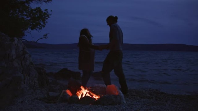 浪漫的情侣在海岸的篝火旁跳舞