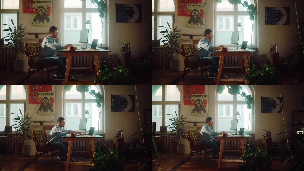 年轻帅哥在正宗阁楼办公室的创意机构的台式电脑上工作。翻新的时尚装饰，配有室内植物、艺术海报和大圆形窗
