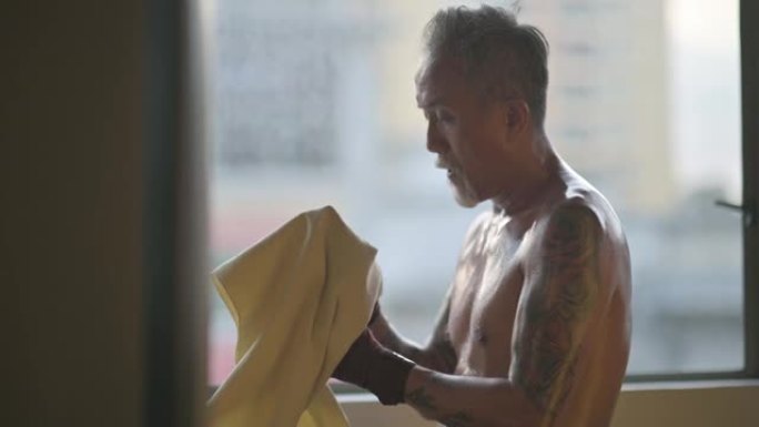 亚洲中国高级泰拳运动员在健身房锻炼后用毛巾擦拭身体