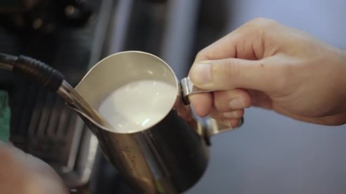 咖啡师手的特写镜头在装有专业咖啡机的水罐中蒸牛奶，用于在咖啡馆中煮咖啡