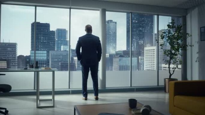 体贴的非洲裔美国商人穿着一件完美的西装，站在他的办公室里，看着窗外的大城市。成功的首席执行官为电子商