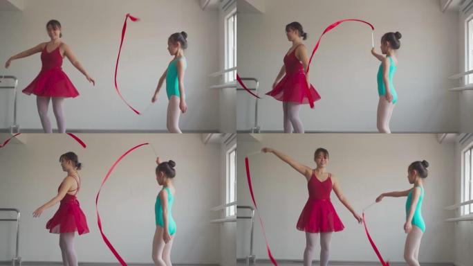 慢动作亚洲中国少女在体操学校和小学生一起用彩带练习艺术体操。芭蕾舞学校。