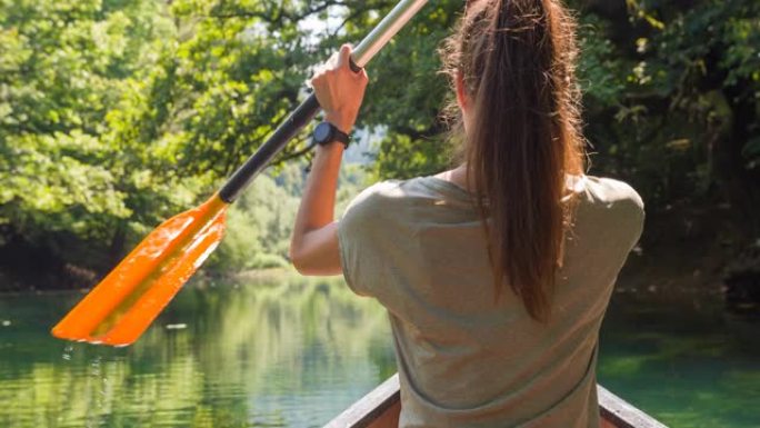 夏天，年轻女子在令人惊叹的郁郁葱葱的绿色河上划独木舟