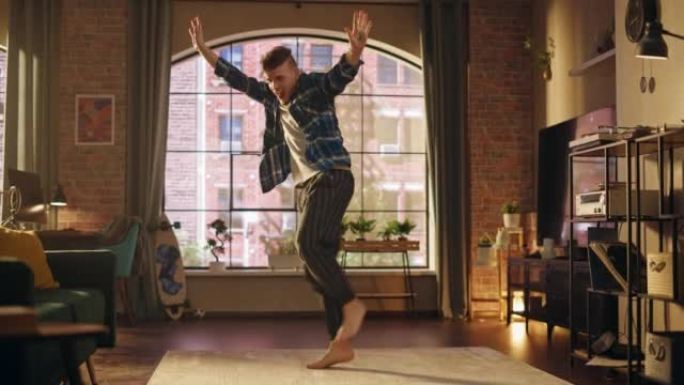 英俊的年轻男性穿着舒适的家装跳舞，在阁楼公寓为自己举办派对。为社交媒体录制有趣的病毒视频。