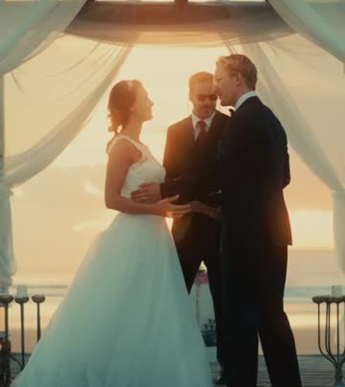 垂直屏幕: 美丽的新娘和新郎在海边的海滩上举行户外婚礼。浪漫夫妇和多民族文化最好的朋友的结婚场所。