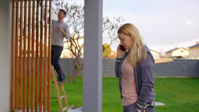 女人在手机上聊天，而男人在背景中画木框