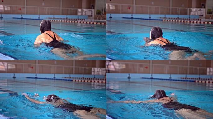 活跃的高级女子在室内游泳池游泳蛙泳