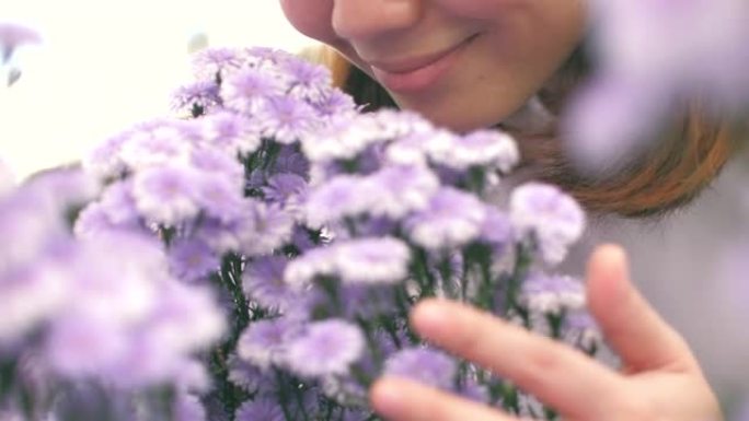 年轻女子幸福，手里拿着紫色的花，在花园里闻到紫色的花