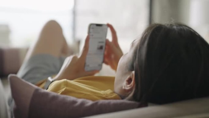 女人躺在沙发上使用智能手机
