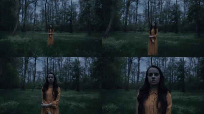 慢动作推入一个穿着橙色连衣裙的怪异黑发女人的镜头，站在空旷的森林里，恐怖的场景