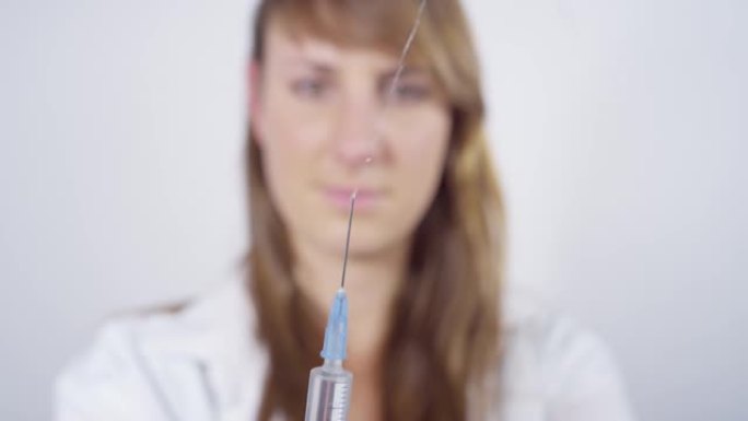 特写: 护士在准备另一枪时，从注射器中挤出疫苗。