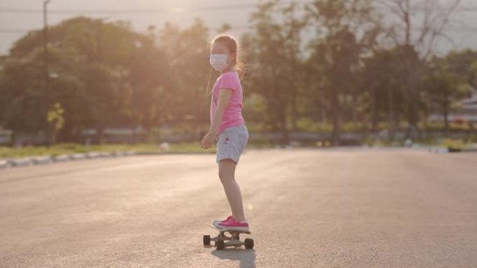 可爱的快乐小女孩，戴着外科口罩，在日落时玩冲浪滑板