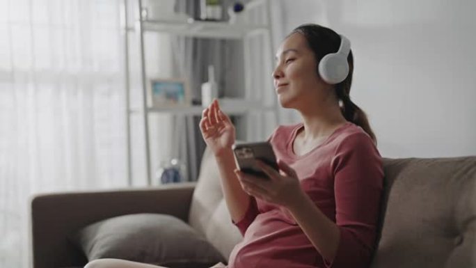 亚洲女性在家中享受智能手机上的音乐