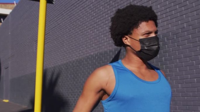 适合非裔美国男子在城市锻炼时戴着口罩，在街上伸展