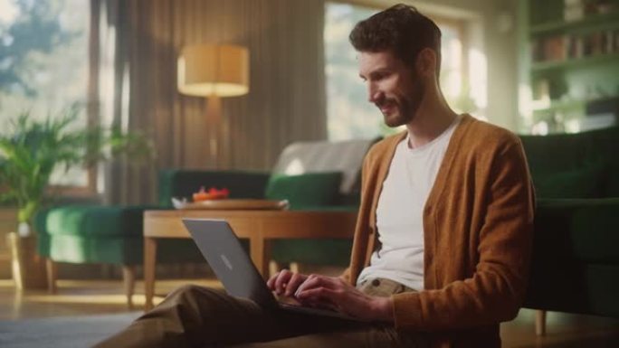 英俊快乐的男人使用笔记本电脑在客厅做远程工作。坐在地板上的男性使用互联网，撰写项目报告。有效而富有成