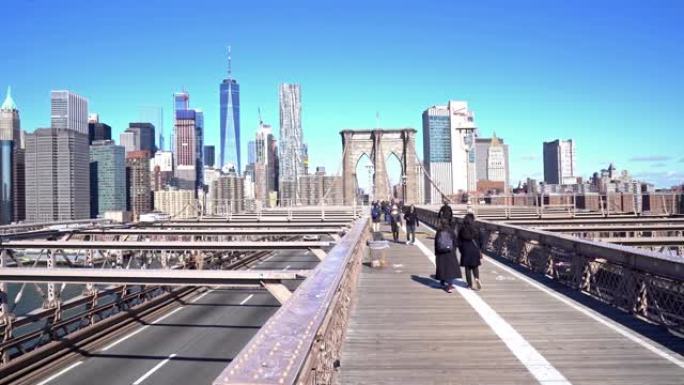 4K UHD Handhel dolly shot: 游客行人在布鲁克林大桥上步行和交通，背景为天际