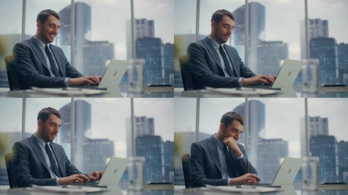 面带微笑的商人，穿着西装，坐在现代办公室的办公桌前，使用笔记本电脑，在窗户旁边，可以看到摩天大楼。成