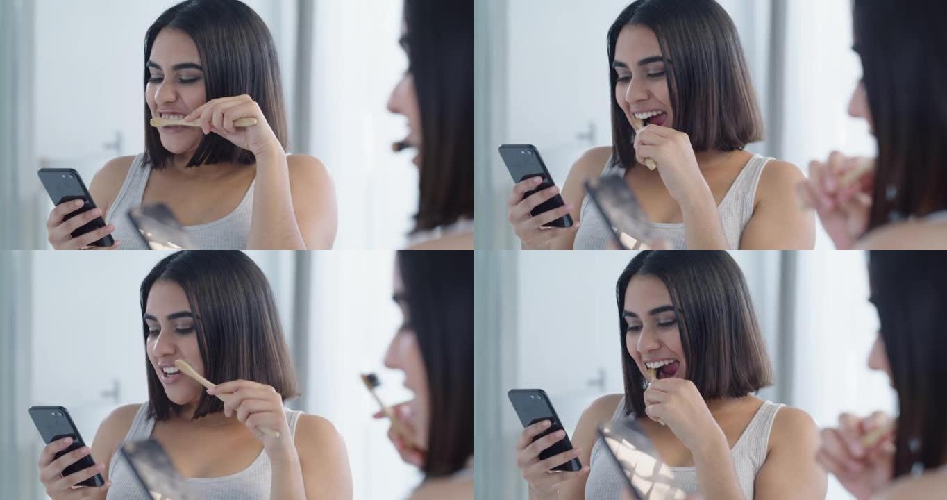 4k视频片段，一名年轻女子在家里的浴室里刷牙时在手机上