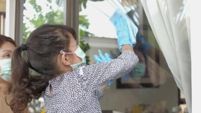 女儿帮助母亲清洁窗户上的玻璃