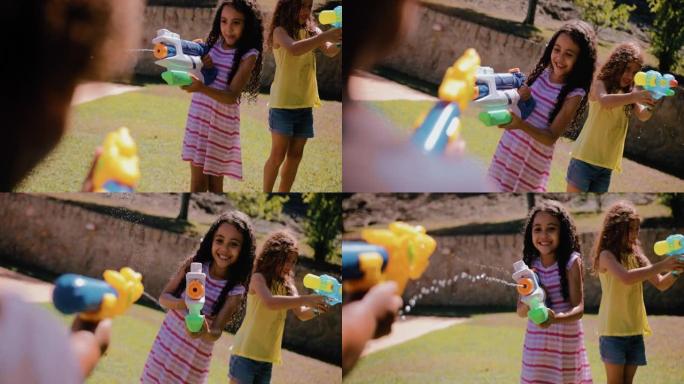 女孩在花园里用水枪向男孩喷水