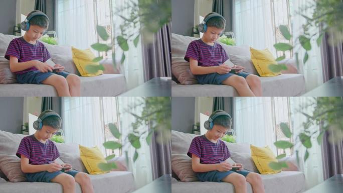 亚洲男学生在家上学的时候用智能手机听在线课。
