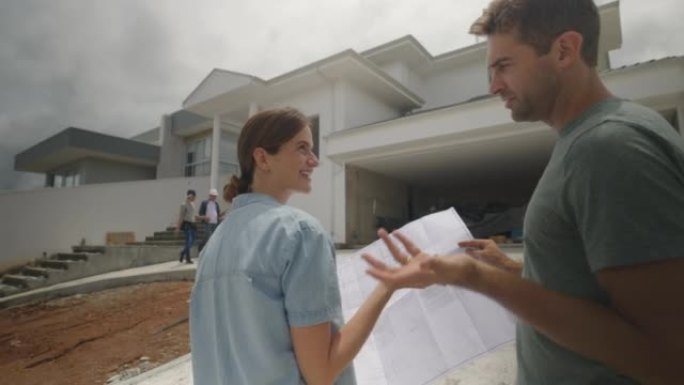 巴西夫妇建造他们梦想中的房子，看着蓝图，同时指着他们家的门面讨论一些事情