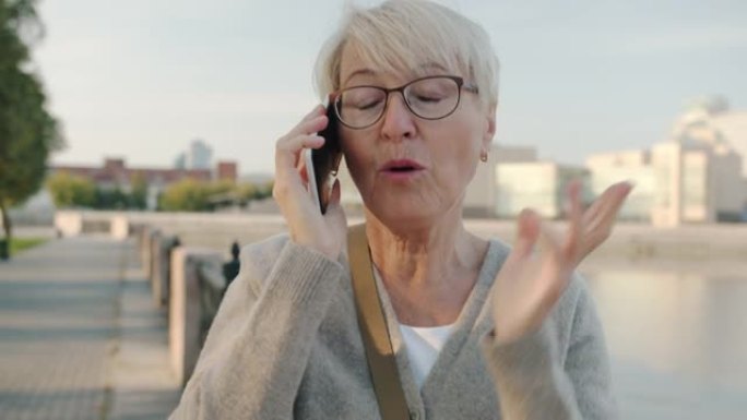 开朗的老太太在手机上聊天微笑独自站在现代城市