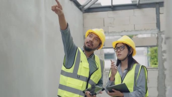 亚洲女建筑师工程师在施工现场与男工程师交谈安装太阳能电池板