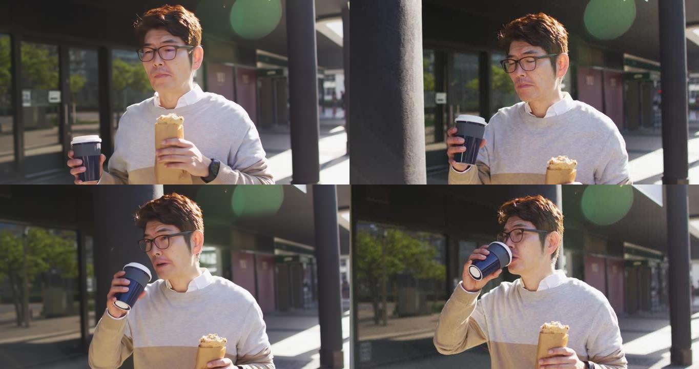 亚洲男子在户外散步时喝咖啡和吃零食