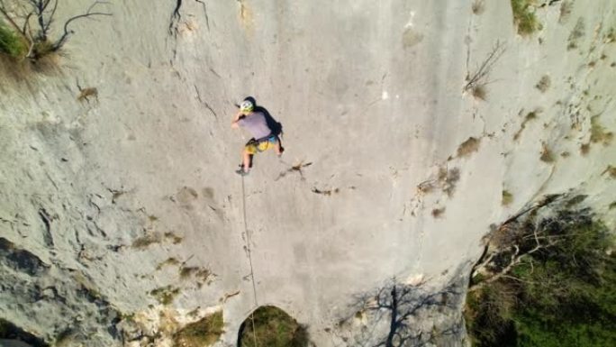 空中: 年轻的男性攀岩者带头攀爬并使用quickdraw连接绳索