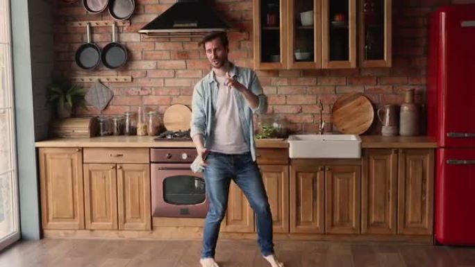 男子在温暖的木地板上的厨房里赤脚跳舞