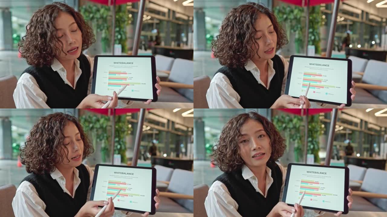 亚洲女性从事商业发展工作，展示数字平板电脑上的信息图表。
