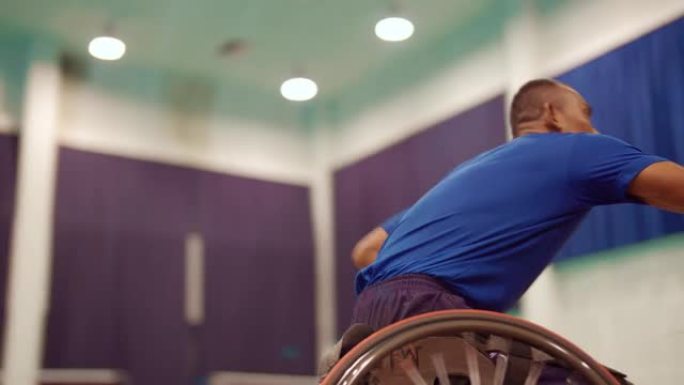 亚洲男子在室内网球场玩和练习轮椅羽毛球。
