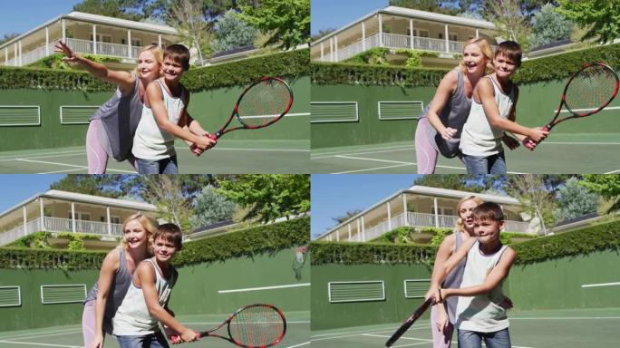 白人母亲在阳光明媚的日子里教儿子在网球场打网球