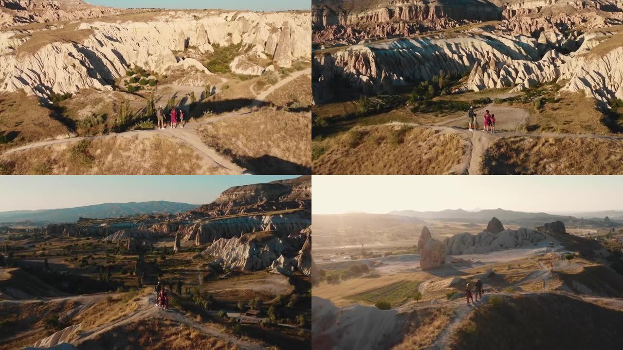 史诗般的电影镜头，无人驾驶飞机在日出山顶上带着孩子在快乐的家庭周围平移，欣赏卡帕多西亚的景色