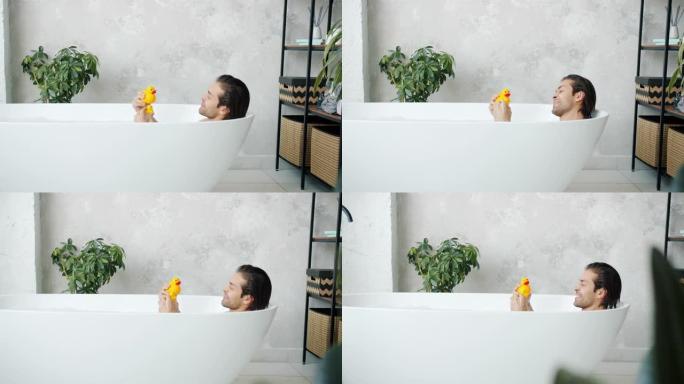 滑稽年轻人玩玩具鸭子在家洗澡的慢动作